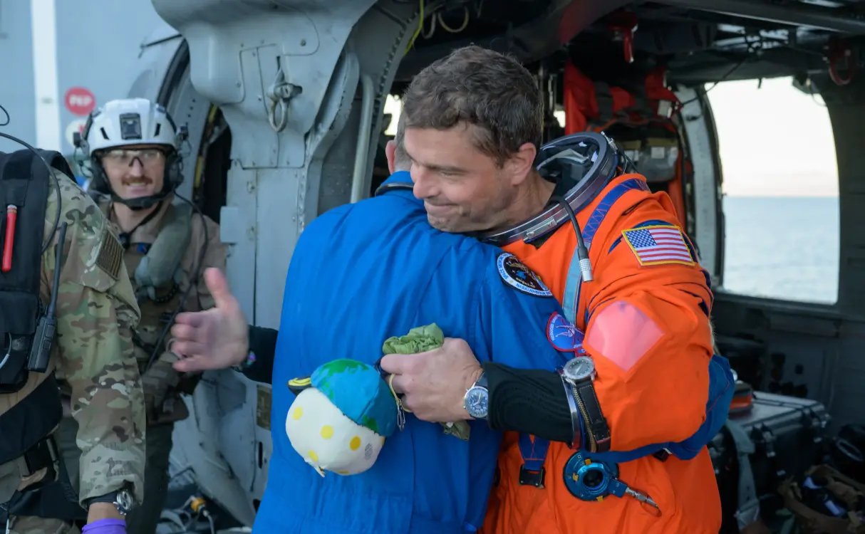 El astronauta de la Nasa Reid Wiseman, comandante de Artemis II, abraza al cirujano de vuelo de la Nasa Richard Scheuring, junto a un helicóptero MH-60 Seahawk de la Armada, procedente de Helicopter Sea Combat. FOTO: NASA
