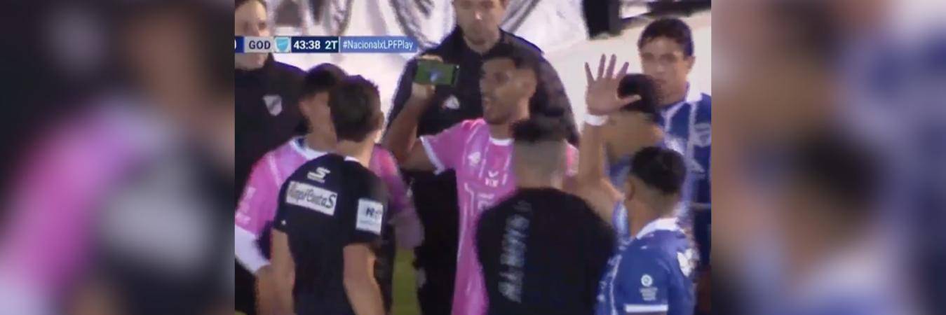 El momento exacto en el que el jugador le muestra el celular al árbitro por una jugada polémica. FOTO: CAPTURA DE PANTALLA TRANSMISIÓN LPD PLAY 