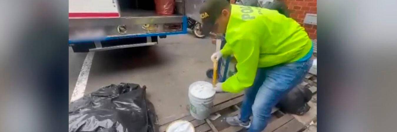 Momento en que los agentes de Policía Aduanera sacaban las armas de las canecas de pintura. /FOTO: CORTESÍA POLICÍA NACIONAL. 