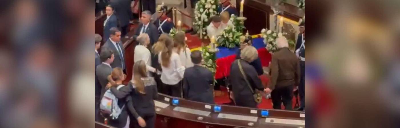 En la imagen se ve a María Claudia Tarazon cargando a su hijo frente al ataúd. /FOTO: CAPTURA DE VIDEO