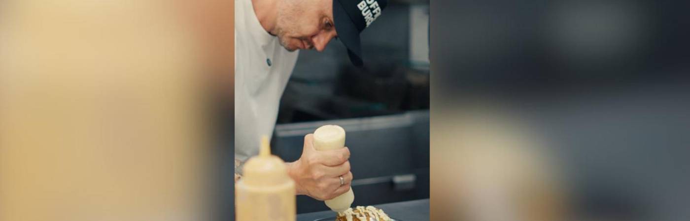 Él es Gustavo Calle preparando una de sus hamburguesas. / FOTO: CORTESÍA