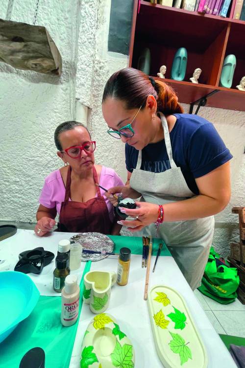 La profesora Diana Tamayo Herrera, de camiseta azul, pasa sin afán por el puesto de cada una de las perticipantes. En la imagen instruye a Claudia Mercado, que la observa atenta. FOTO: JAIDER ESCOBAR