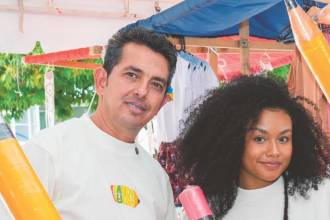 De izquierda a derecha: José; su nuera, Darlin; y su hijo, Deinner, quienes participan en la elaboración y comercialización del lápiz gigante, que también sirve de alcancía. FOTO: CORTESÍA LA PECO